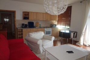 Un espacio habitable compacto con kitchenette, zona de comedor y sala de estar con sofá rojo.