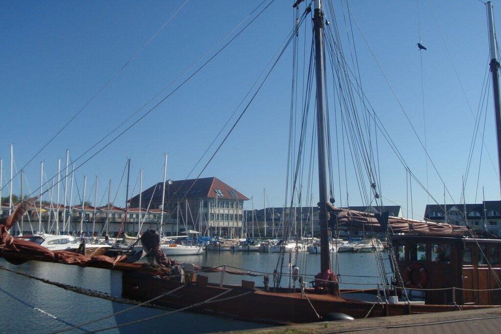 Una marina con barcos amarrados, un edificio de techo rojo y un cielo azul despejado.