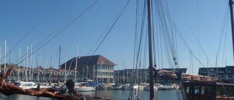 A marina with boats docked, a building with a red roof, and a clear blue sky.