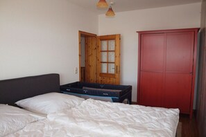 A bedroom with a bed, a wooden wardrobe, and a suitcase. - Karlshagen at the harbor (Karlshagen Usedom)