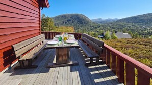 A wooden deck with a table set for dining, overlooking a mountainous landscape. - Amazing home in Tjørhom with sauna (Tjørhom)