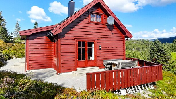 A red cabin with a deck, a chimney, and a window. - Amazing home in Tjørhom with sauna (Tjørhom)