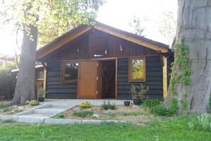 A log cabin with a wooden door, two windows, and a small porch area. - Holiday home with 2 bedrooms (Grünheide)