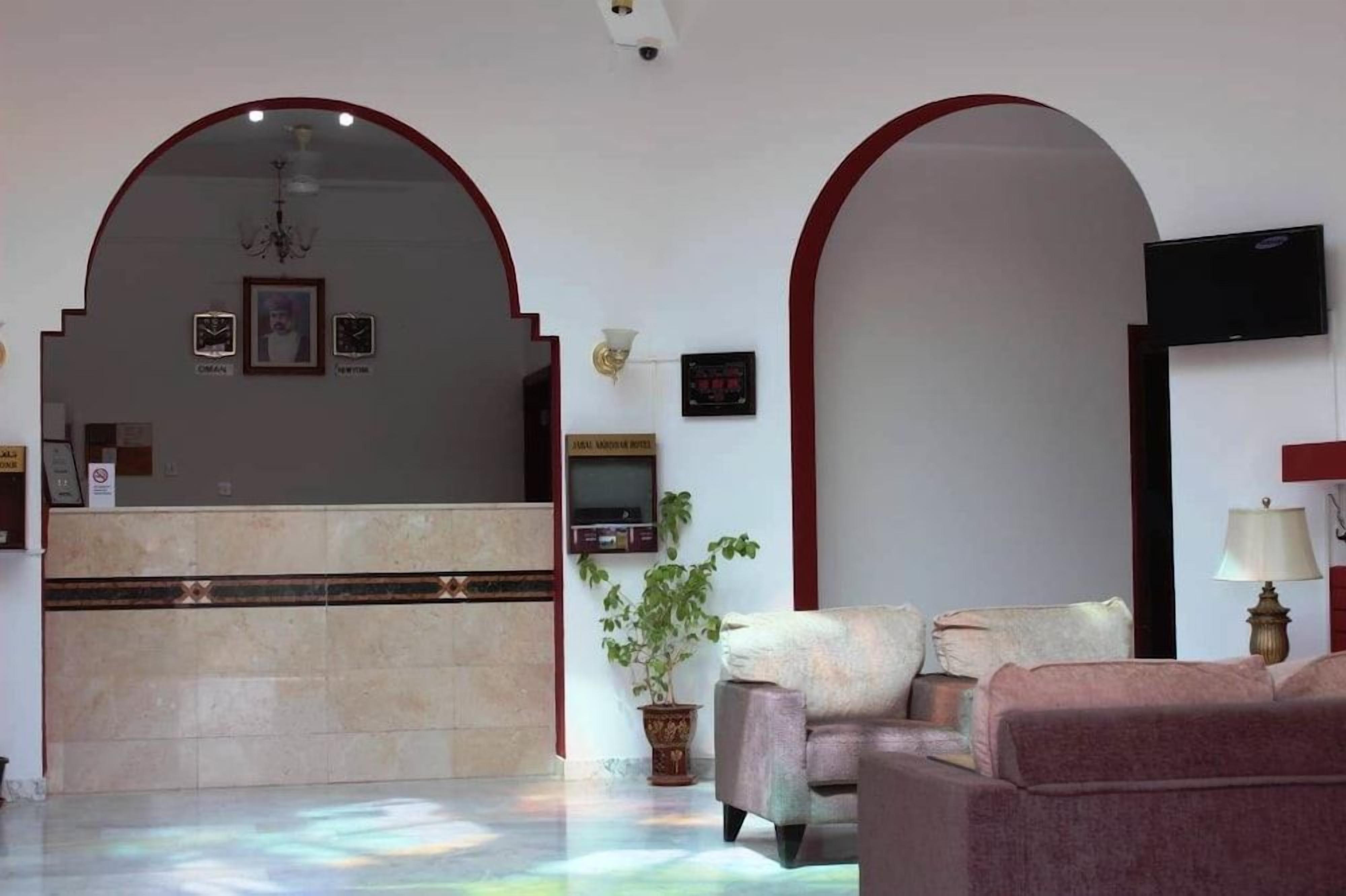 Un hall con mostrador de recepción, zona de estar y un televisor montado en la pared.