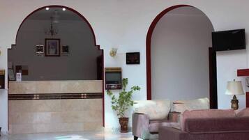 Un hall con mostrador de recepción, zona de estar y un televisor montado en la pared.