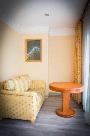 Une pièce comprenant un canapé, une table ronde en bois et un tableau accroché au mur.
