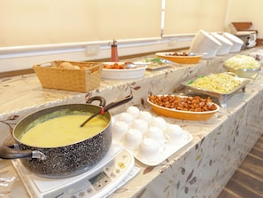 A buffet table with various food items and a pot of soup on a portable stove. - OYO 44047 Sun Hotel Tosu (Tosu)