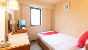 Habitación de hotel con una cama, un escritorio con lámpara, televisor y ventana.