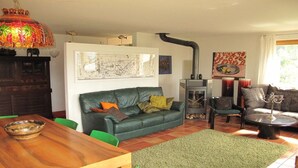 A living room with a green sofa, a wooden dining table, and a fireplace.