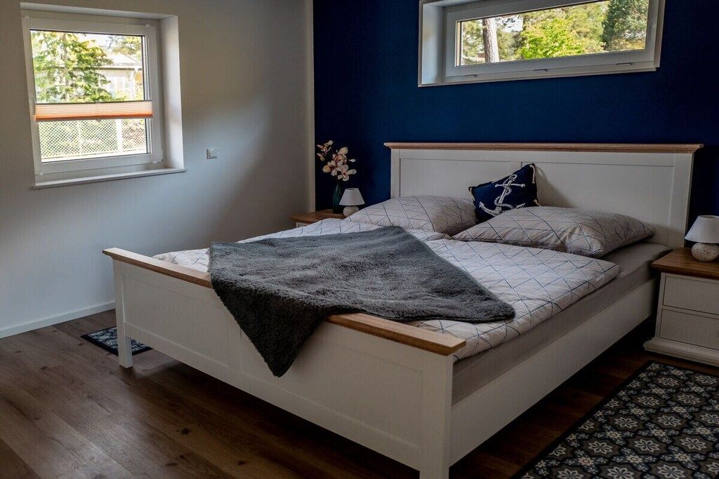 A bedroom with a bed, two bedside tables, a window, and a nightstand with a lamp.