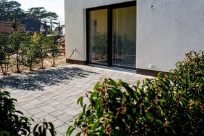 A modern building with a large glass door and a paved patio area. - Holiday apartment with 2 bedrooms (Lubmin, Deutschland)