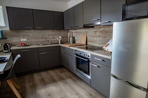 A modern kitchen with dark cabinets, a stainless steel refrigerator, and a wooden countertop. - Holiday apartment with 2 bedrooms (Lubmin, Deutschland)