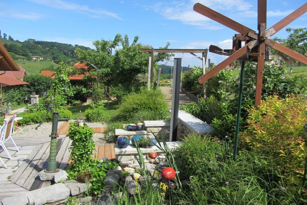 Un jardín con un molino de madera, escalones de piedra y una terraza de madera.