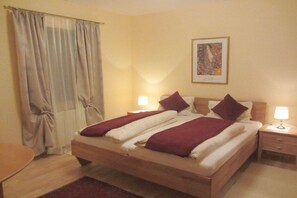Une chambre d’hôtel avec un lit, deux tables de chevet, une lampe, un rideau et un tableau au mur.