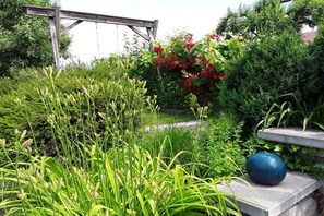 A garden with various plants and a blue spherical object on a stone ledge. - 1 in the romantic guesthouse Annas-Home (Ratsch)
