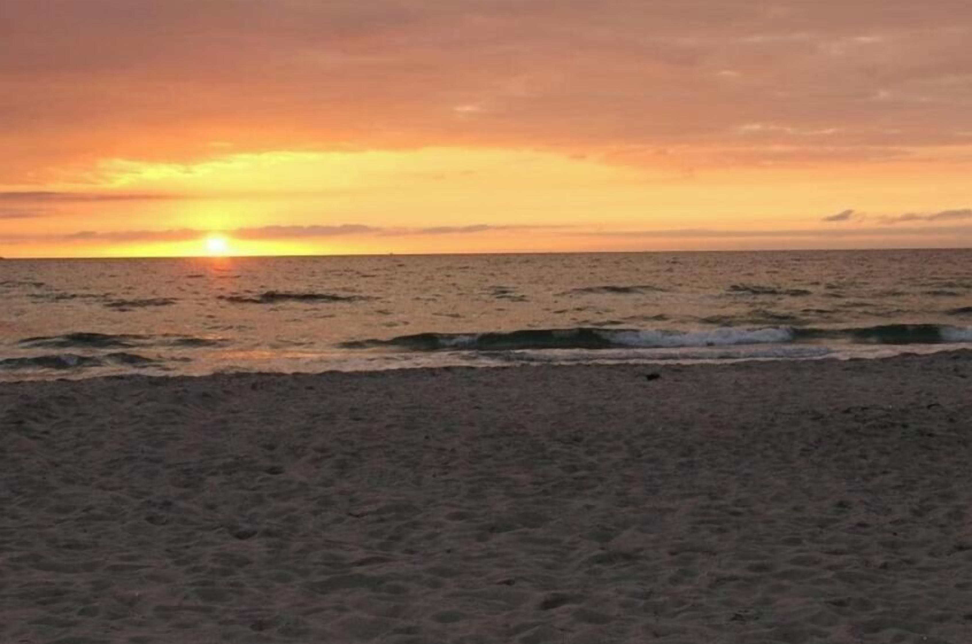 Een strand met een zonsondergang boven de oceaan.