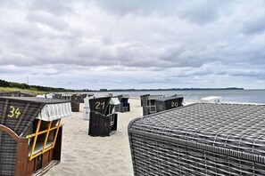 Eine Reihe von nummerierten Strandhäusern direkt am Strand, mit Blick auf das Meer.