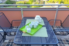 Ein Balkon mit einem Tisch, gedeckt für Tee, inklusive Tassen, Teekanne und Tablett.