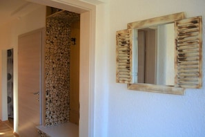 A hallway with a door leading to a room with a wall covered in stacked logs. - House Sunshine - Apartment Sun Greeting - Ground Floor (HERMAGOR-PRESSEGGER SEE)