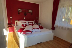 A bedroom with a bed, a nightstand, a wall clock, and a window with curtains. - House Sunshine - Apartment Sun Greeting - Ground Floor (HERMAGOR-PRESSEGGER SEE)