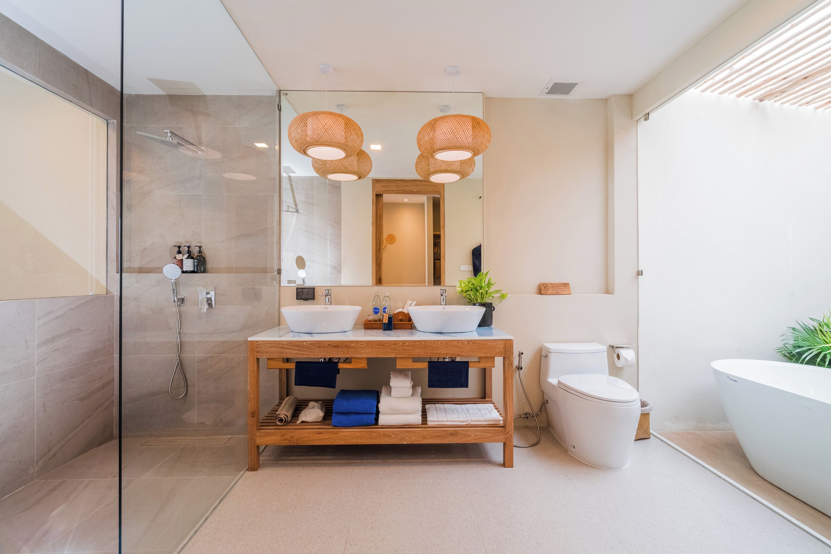 Un baño moderno con cabina de ducha de vidrio, tocador de madera con dos lavamanos y una bañera grande.