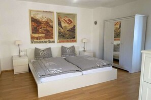 A bedroom with a bed, two nightstands, a wardrobe, and two posters on the wall.