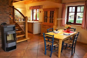 A cozy kitchen with a wooden table, chairs, and a stove. - Holiday home with 1 bedroom (Ostseebad Prerow)