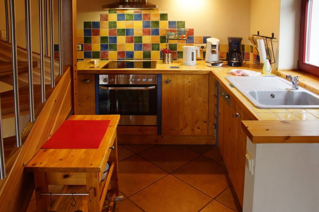 A compact kitchen with a wooden countertop, a built-in oven, and a tiled backsplash.