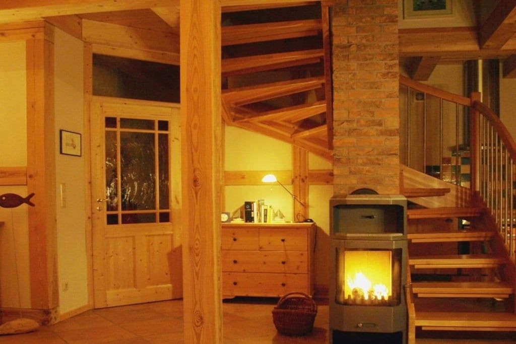 Ein Holzinnenraum mit Kamin, einer Holztreppe und einer Tür zu einem anderen Raum.