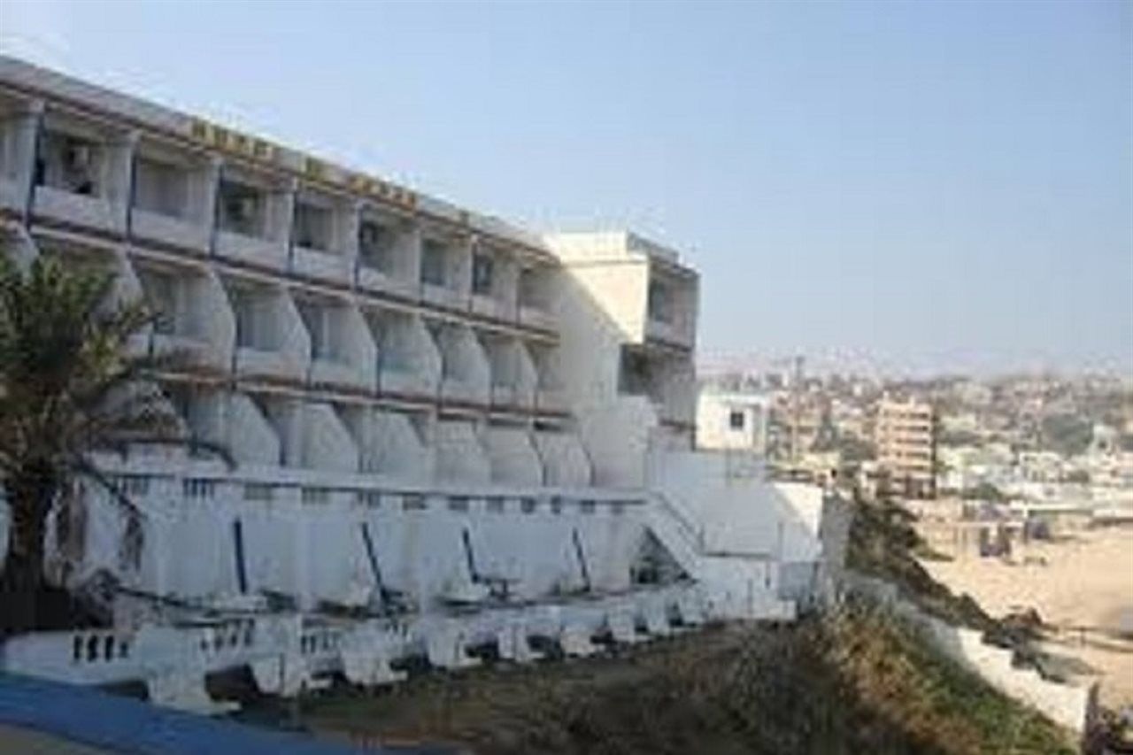 A multi-story building with balconies, located near a beach.