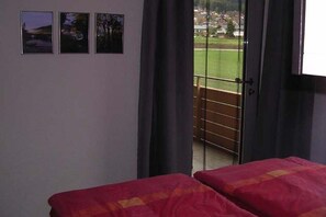Ein Zimmer mit einem Bett, einem Vorhangfenster und Blick auf eine grüne Landschaft.