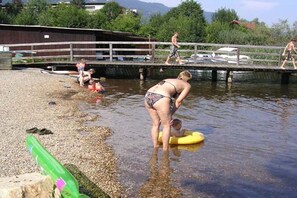 Une personne en maillot de bain, debout dans une eau peu profonde, tenant un flotteur jaune.