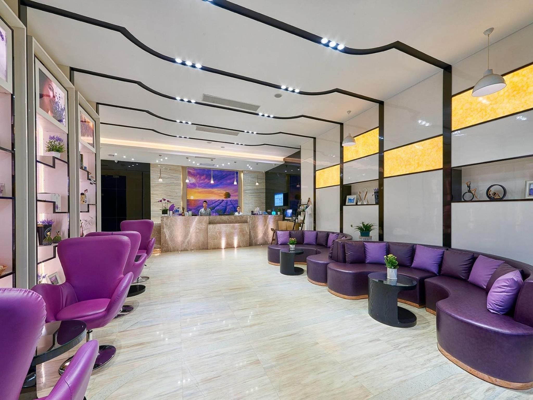 A modern interior with a reception desk, purple seating, and a mural on the wall.