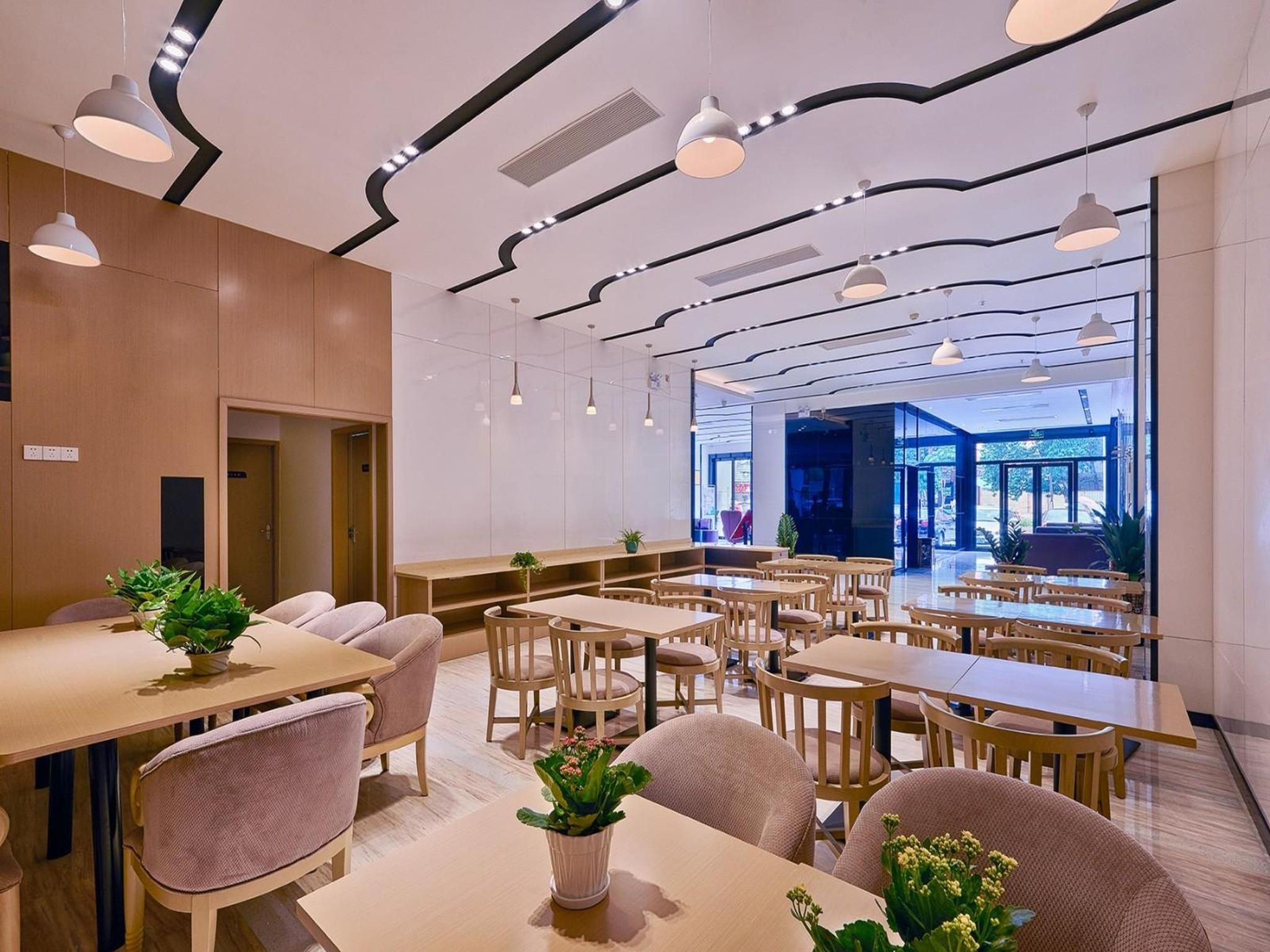 A modern dining area with multiple tables and chairs, ceiling lights, and a view of the outdoors.