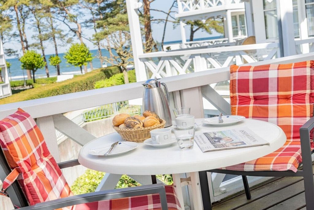 Ein Balkon mit einem Frühstückstisch, gedeckt mit Brot, Kaffee und Tee.