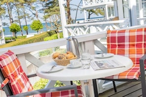 Ein Balkon mit einem Frühstückstisch, gedeckt mit Brot, Kaffee und Tee.