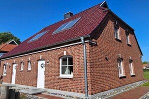 Ein rot genetztes Gebäude mit einem geneigten Dach, einer weißen Tür und einem kleinen Fenster.
