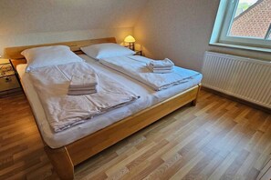 Ein Doppelbett mit weißen Leinen und Handtüchern, eine Nachttischlampe und ein Fenster mit Blick auf ein Backsteingebäude.