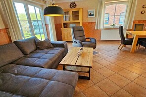 Ein Wohnzimmer mit einer Couch, einem Holztisch und einem Essbereich mit Stühlen und einem Tisch.