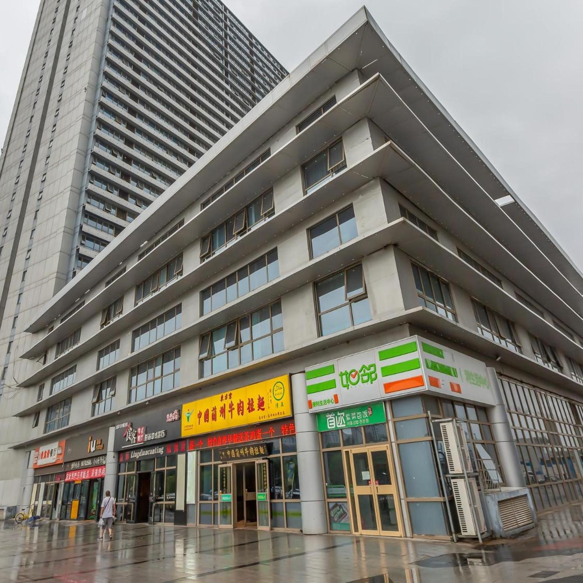 A multi-story building with commercial establishments on the ground floor, including a restaurant and a convenience store.