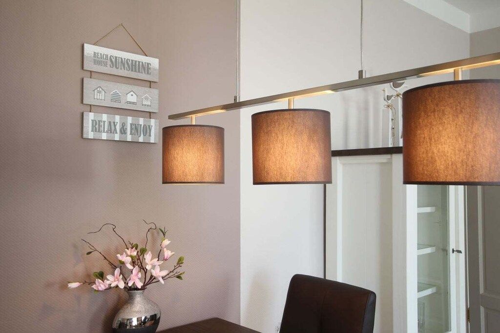 A dining area with a table, chairs, a vase with flowers, and wall-mounted lamps.