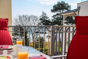 A balcony with a table set for breakfast, including plates, glasses, and orange juice. - Beach oasis - 1st row by the sea (Ostseebad Binz)