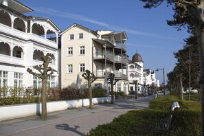 A street with multi-story buildings, including a building with a dome and balconies. - Beach oasis - 1st row by the sea (Ostseebad Binz)