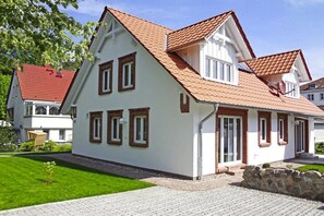 A two-story house with a sloped roof, white exterior walls, and a stone foundation. - The Seibert Baltic Sea House (Graal-Müritz)