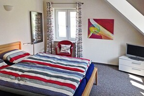 A bedroom with a bed, a chair, a TV, and a window with curtains. - The Seibert Baltic Sea House (Graal-Müritz)