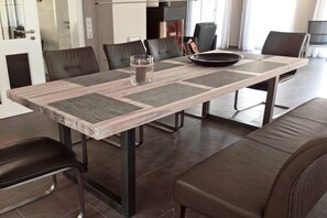 Un espace repas moderne avec une longue table, des chaises noires et un banc.