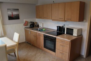 Una cocina compacta con muebles de madera, lavavajillas, estufa y microondas.