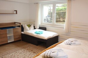A bedroom with a bed, a wooden wardrobe, a window with curtains, and a view of the outside. - Holiday apartment with 1 bedroom (Dresden)