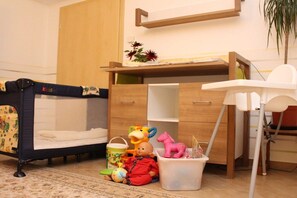 Una habitación infantil con una cuna, un escritorio y varios juguetes.
