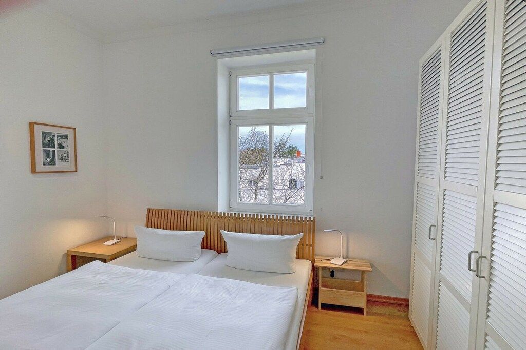 Une chambre à coucher avec un lit, des tables de chevet, une fenêtre et une armoire.
